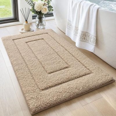 Le tapis de bain est en laine épaisse et présente un poil épais de couleur blanche.