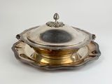 an antique silver plate with a lid and a saucer on it