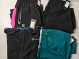 Trois paires de pantalons de course et une paire de chaussures de course sont disposées sur une table.