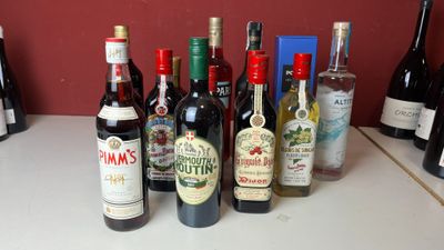 Des bouteilles de vin sont alignées sur un comptoir devant un mur rouge