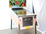 a pinball machine in a room with a curtain behind it