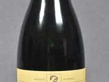 bottle of red wine with a red cap on a grey background