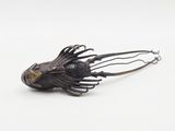 a metal fish head with a long nose on a white surface