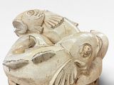 a white sculpture of a fish and a fish on top of it