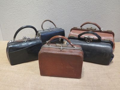 three small leather suitcases are lined up on a table