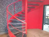 a red spiral staircase in a room with a brick wall