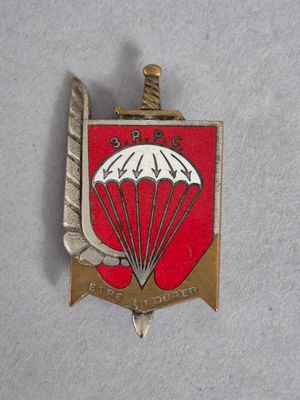 une image représentant un insigne rouge et blanc sur lequel figure un parachute