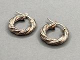 two pairs of silver hoop earrings on a gray surface