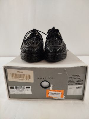 les chaussures noires sont posées sur une boîte, posée elle-même sur une surface blanche