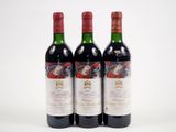 trois bouteilles de vin rouge posées l'une à côté de l'autre sur une surface blanche