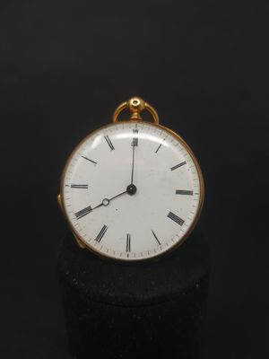 a small gold pocket watch on a black surface
