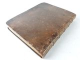 an old book with a brown cover sitting on top of a white surface