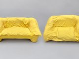 two yellow chairs with covers on them sitting next to each other