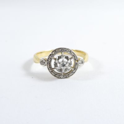 a close up of a diamond and gold ring on a white surface