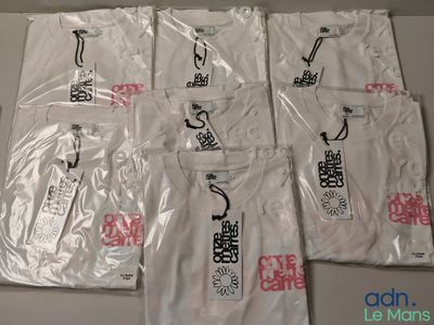 six t-shirts blancs ornés de caractères chinois, posés sur une table