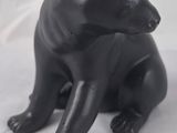 une statue d'ours noir assis sur une surface blanche