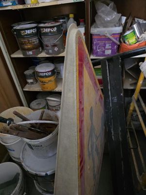 une étagère remplie de pots de peinture et de seaux dans une pièce