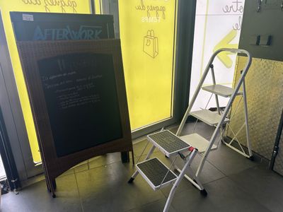 un petit tabouret posé à côté d'un tableau noir posé à même le sol