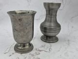 two silver vases sitting on a marble surface