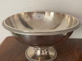 a silver bowl on a wooden table with a white wall in the background
