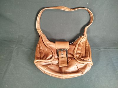 brown leather purse sitting on top of a green cloth covered table