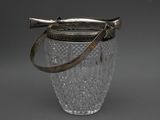 a glass vase with a metal handle on a gray background