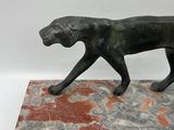 statue of a black cat walking on a red and grey marble base