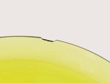 a close up of a yellow bowl on a white surface