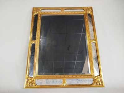 un miroir à cadre doré accroché au mur au-dessus d'un lavabo