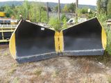 two black and yellow snow plows sitting on the ground