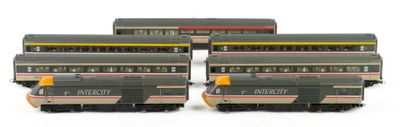 four model trains are lined up on a white surface