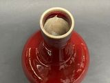 a red vase with a white top sitting on a table