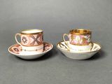 two cups and saucers are sitting on a gray surface