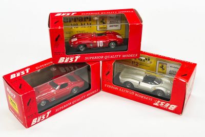 trois petites voitures moulées sous pression, rouges et blanches, dans leurs boîtes, posées sur une surface blanche