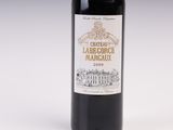 a bottle of red wine sitting on top of a white table