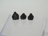 three pieces of black stone sitting on top of a clear box
