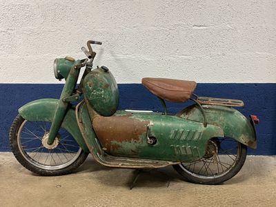 rusty green motorbike parked in front of a blue and white wall