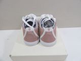 pink and white tennis shoes on a white box on a white surface