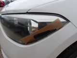 the headlight of a white car with a piece of cardboard sticking out of it