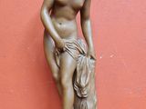 une statue en bronze d'une femme assise sur un rocher