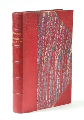an old book with a red cover sitting on top of a white table