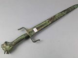a green and black dagger with a lion head on it
