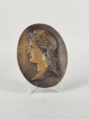 a bronze plate with a woman ' s head and a bird on it