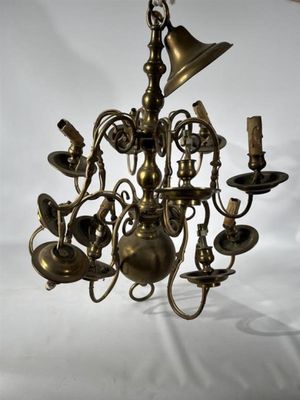 un lustre ancien en laiton à cinq branches, surmonté d'une clochette suspendue au plafond