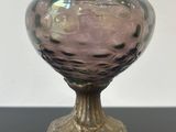 a purple glass vase on a stand on a table