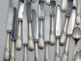 a lot of silver spoons and knives on the table