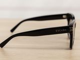black sunglasses on a wooden table with a white wall in the background