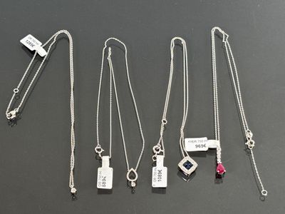 six different necklaces with different designs on a black surface
