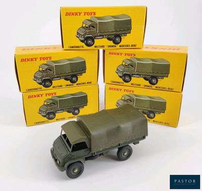 quatre camions militaires miniatures posés devant une pile de cartons