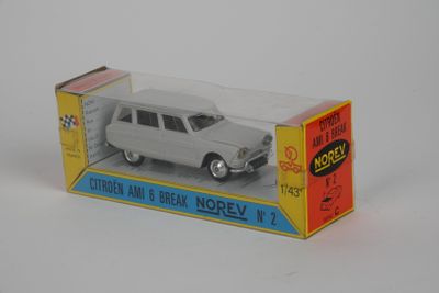 une petite voiture blanche dans une boîte, posée sur une surface blanche